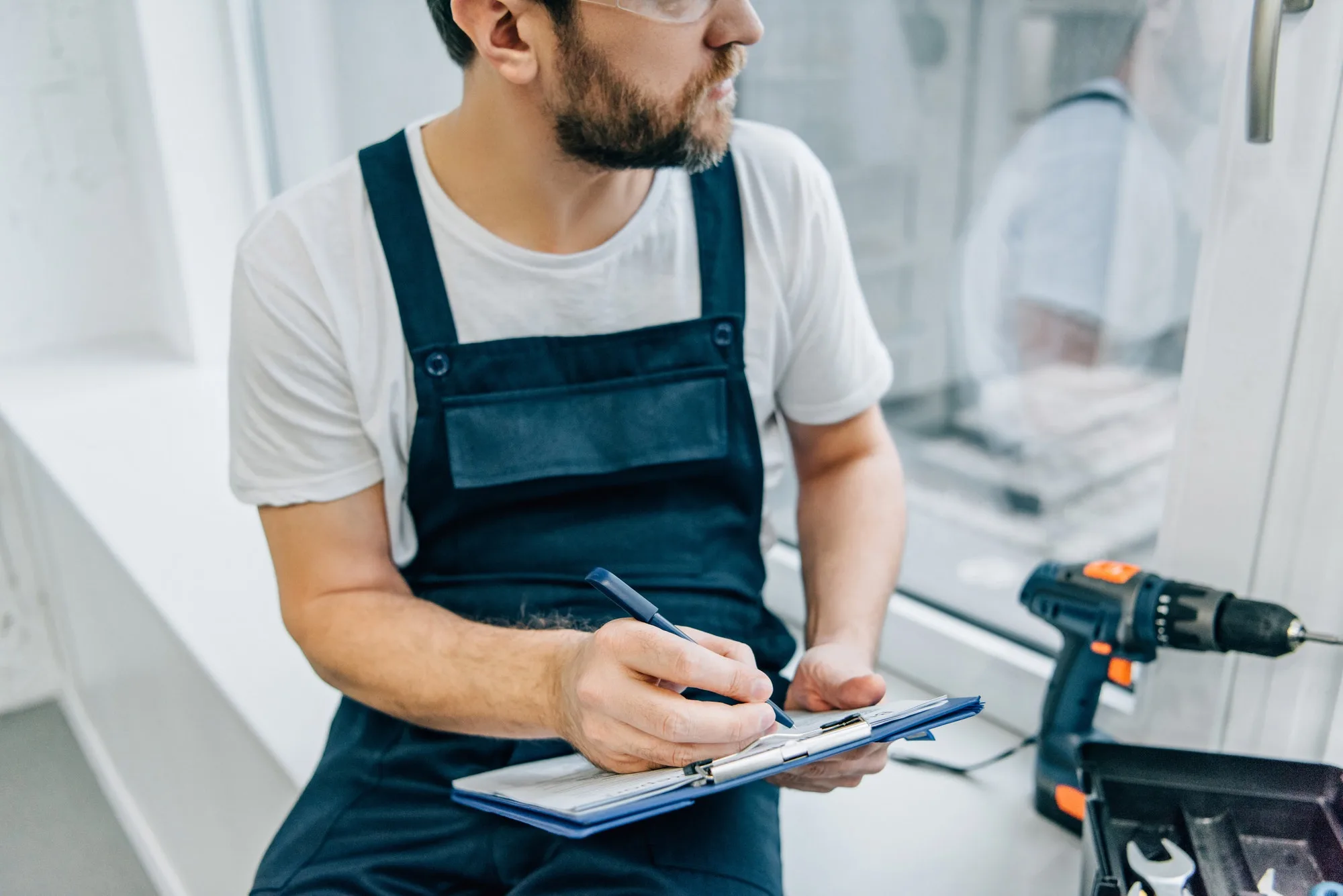 Technician recording window measurements on a clipboard
